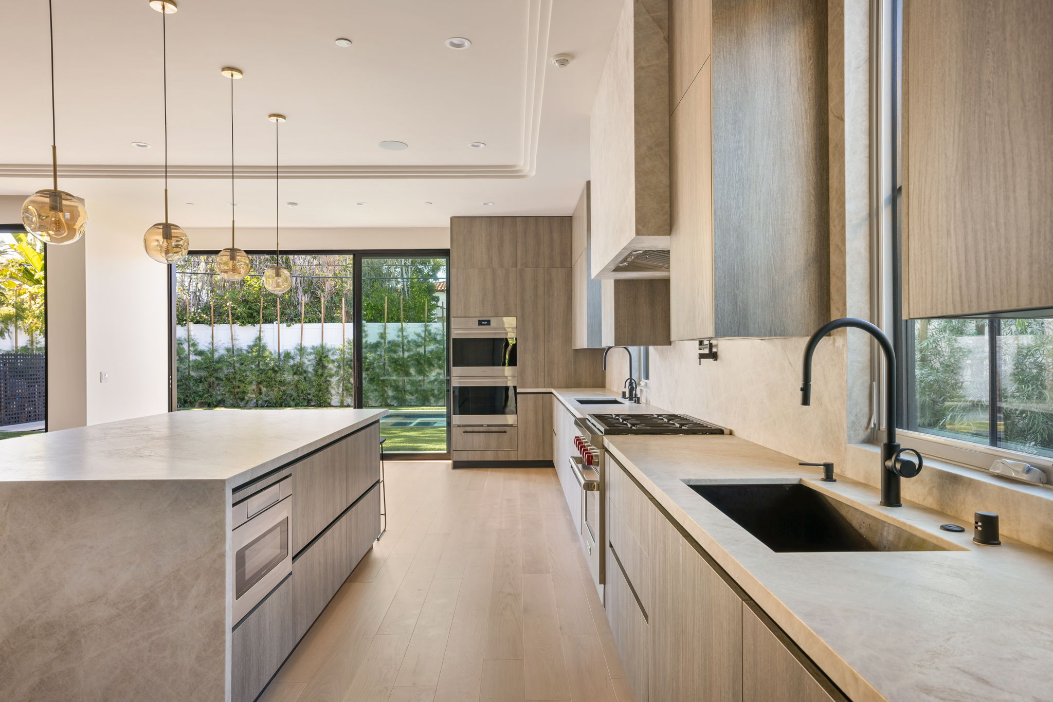 The Alder House kitchen with waterfall stone island and pool view