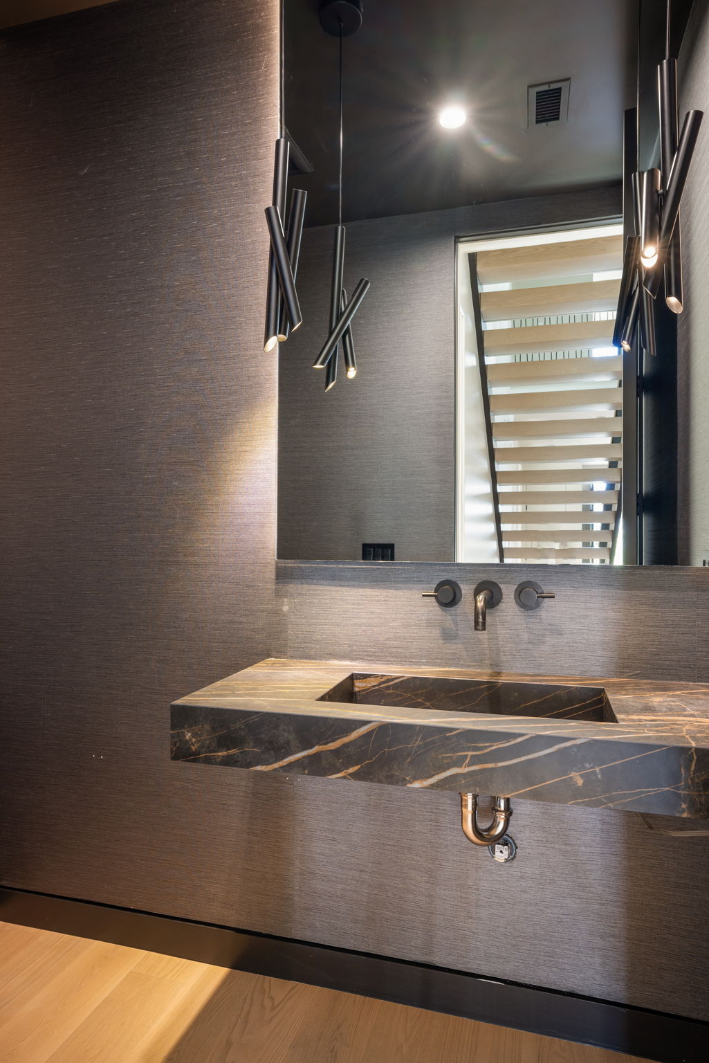 The Alder House powder room with dark marble sink and linear pendant lighting