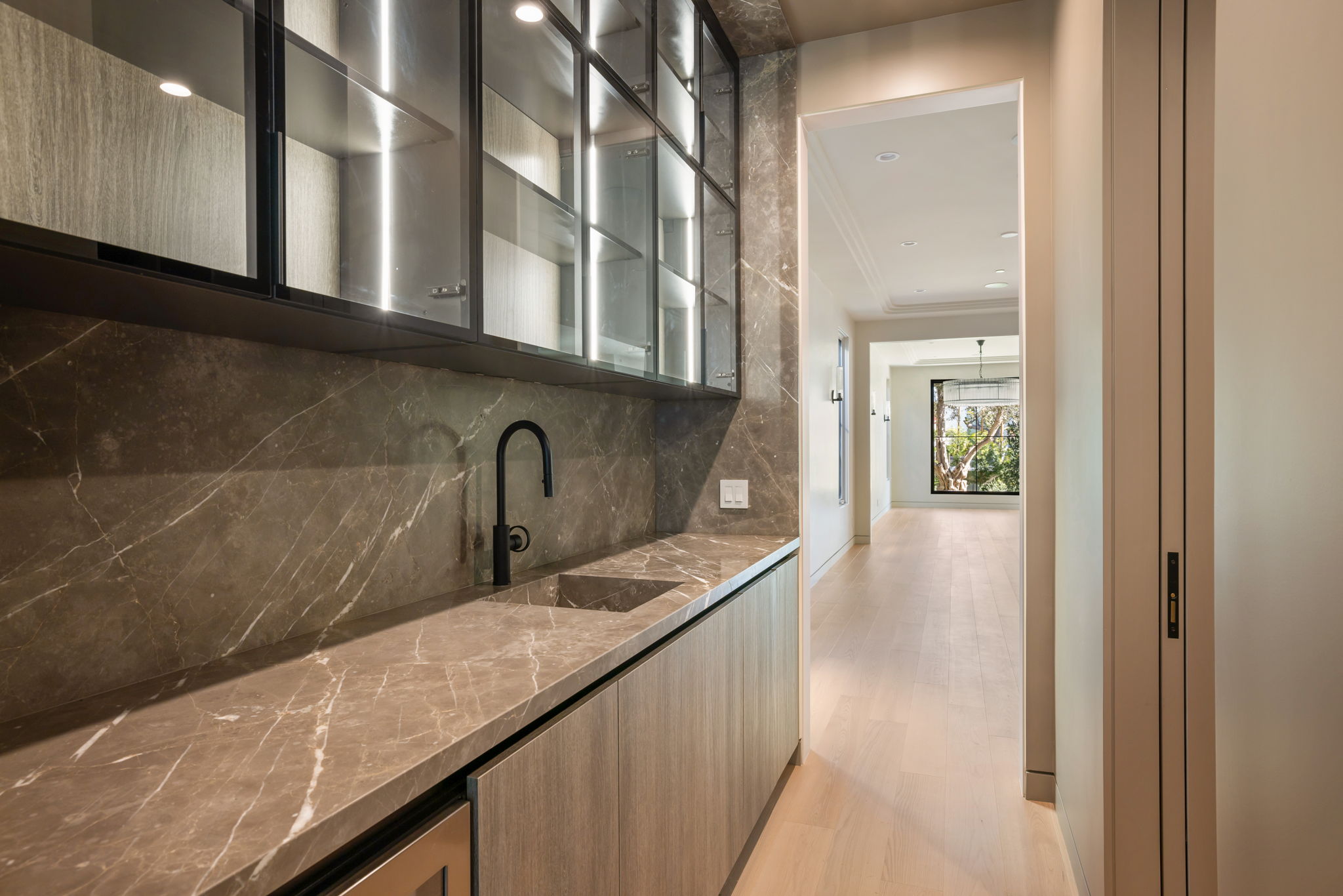 The Alder House wet bar with marble backsplash and glass cabinetry