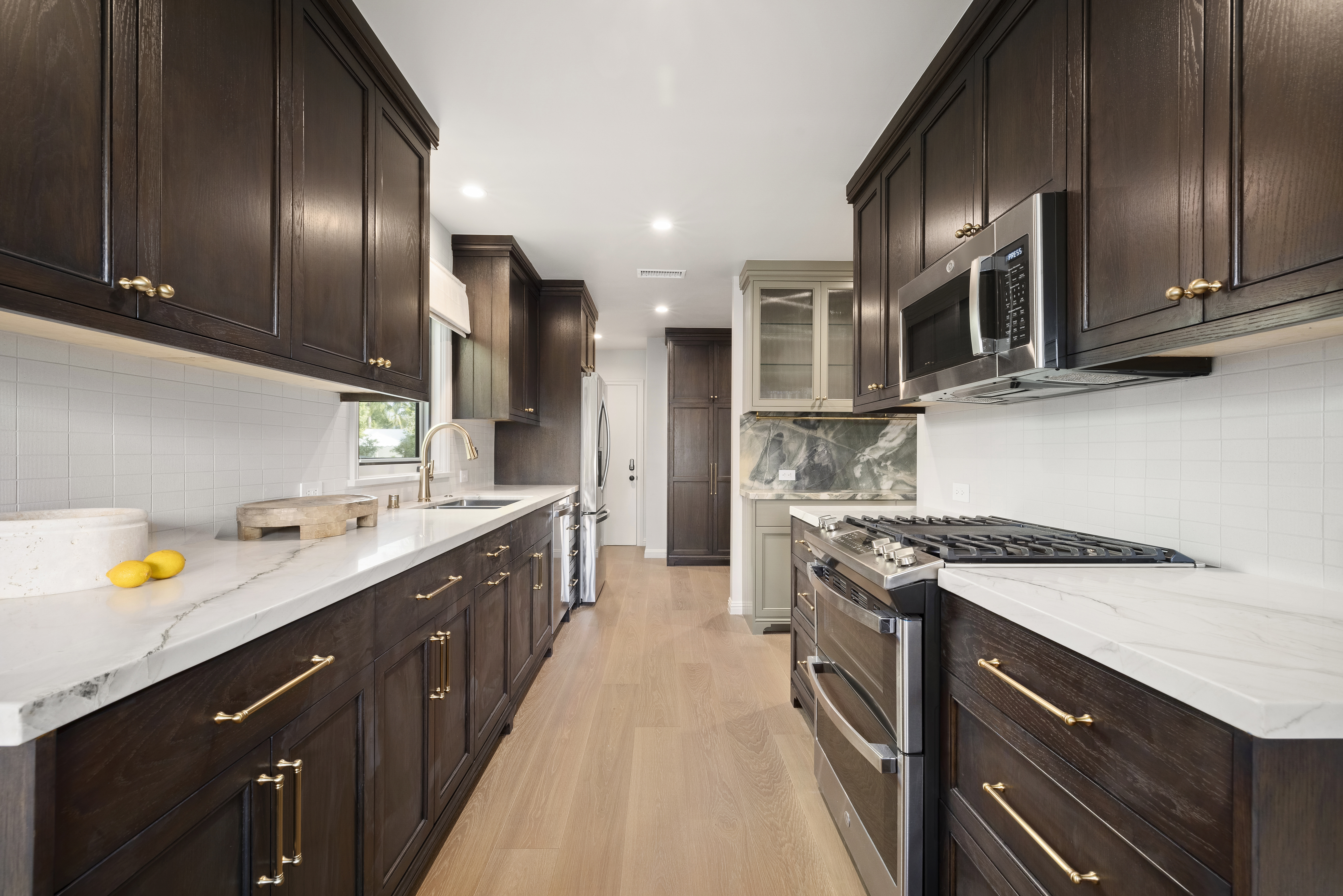 Casa Lista galley kitchen with dark wood cabinetry and brass hardware