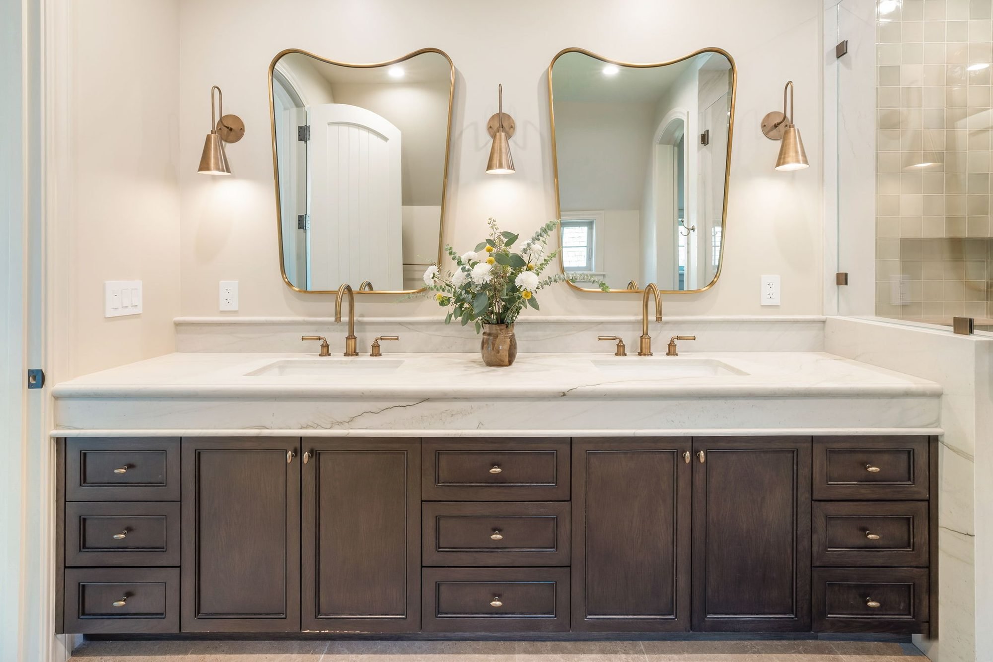 Storybook House primary bath double vanity with curved brass mirrors