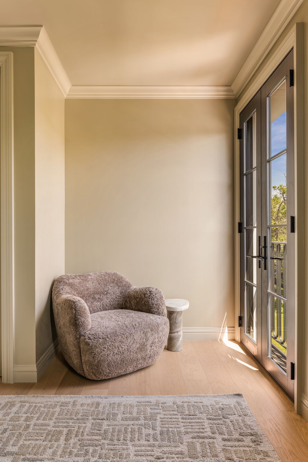 The Thistle House bedroom sitting nook with shearling chair and french doors