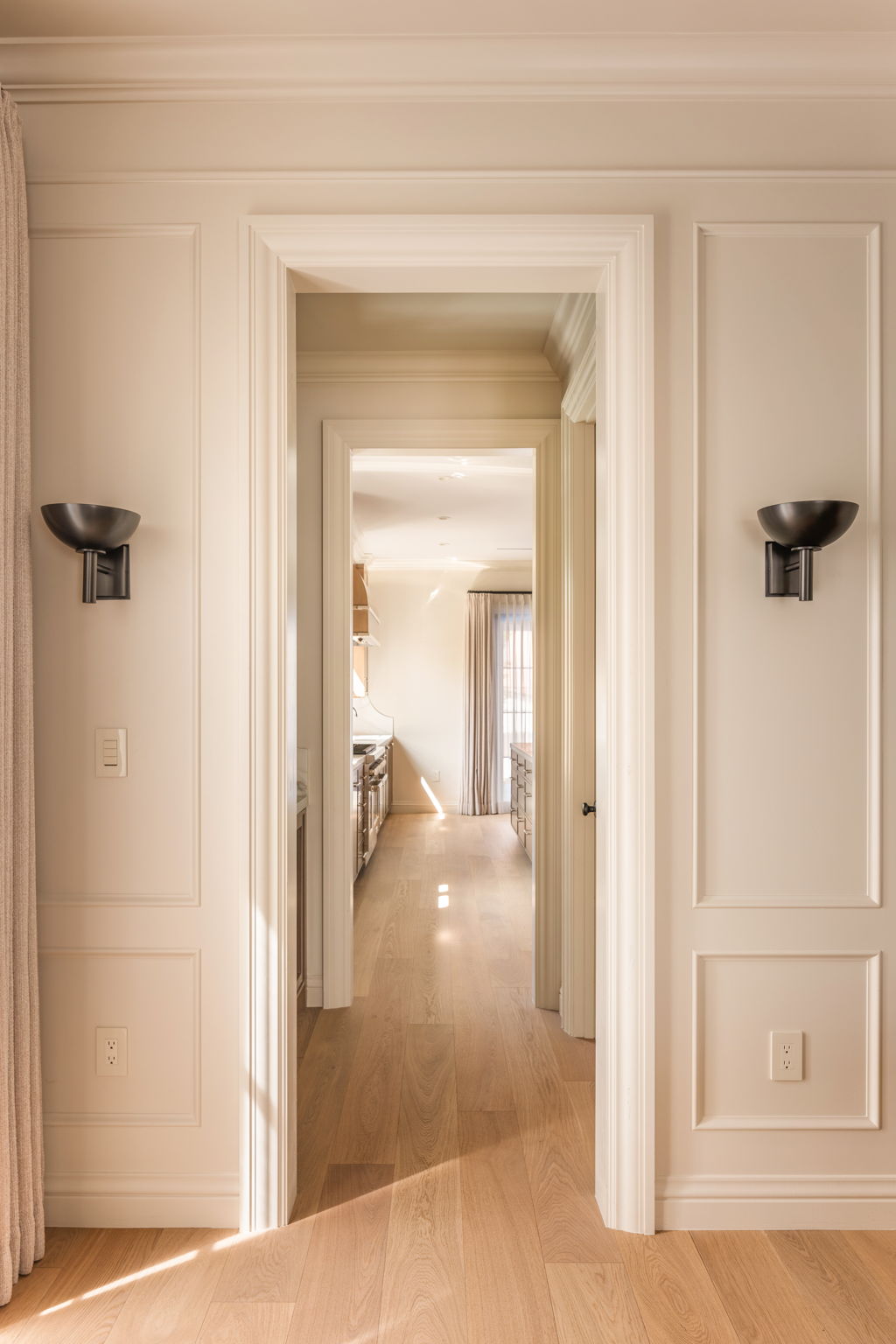 The Thistle House hallway with wall sconces leading to the kitchen