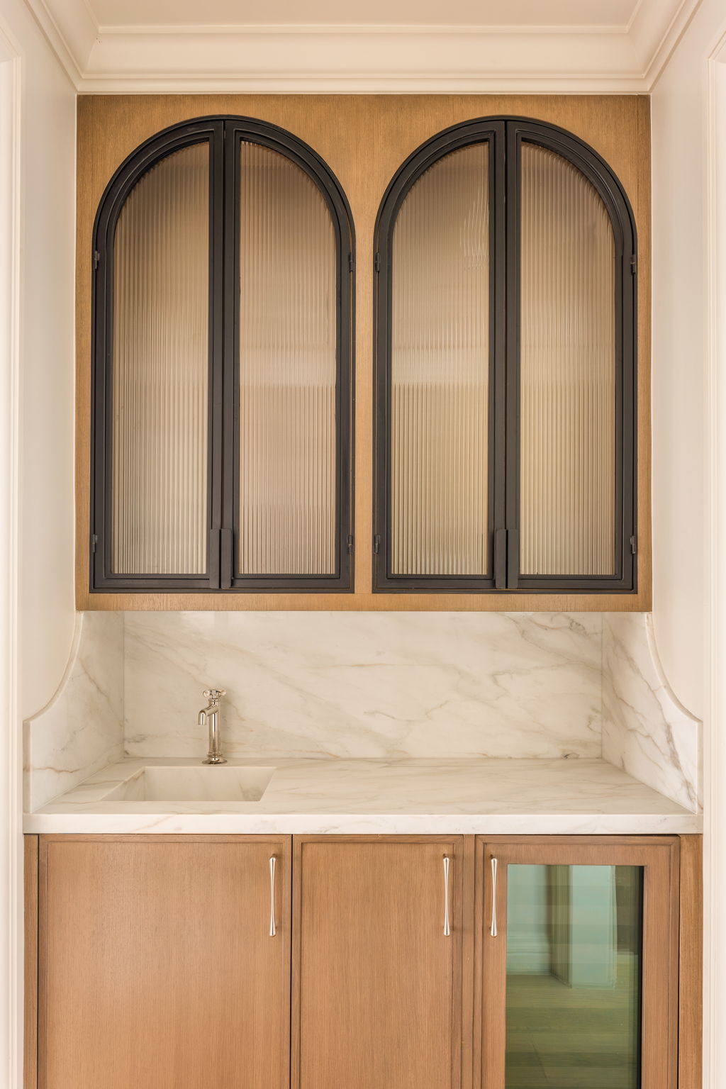 The Thistle House wet bar with arched glass cabinet doors and marble backsplash