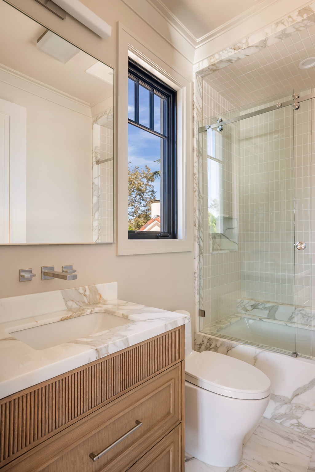 The Verdigris House guest bath with fluted oak vanity and marble shower