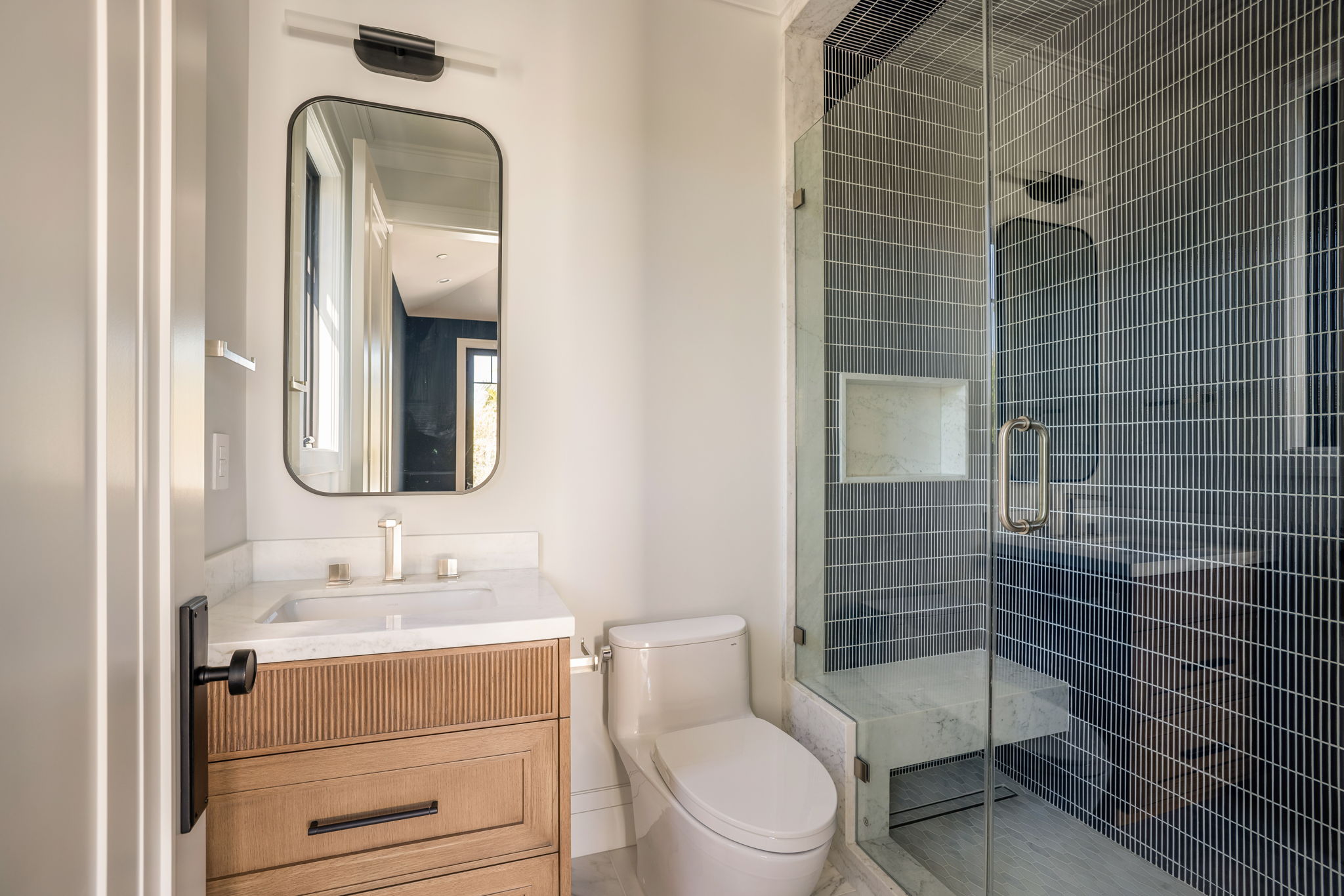 The Verdigris House guest bath with navy mosaic tile shower and marble bench