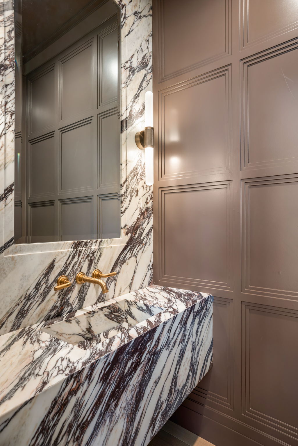 The Verdigris House powder room with sculptural marble trough sink and mauve paneled walls