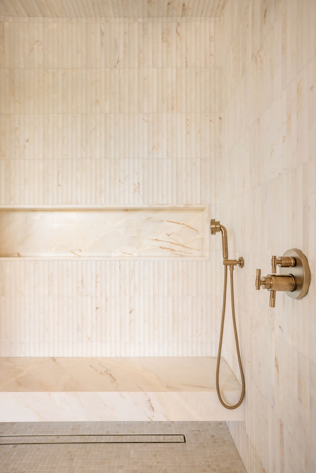 The Verdigris House primary shower with fluted marble tile and brass fixtures